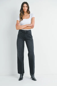 Woman wearing white square-neck top and black relaxed fit straight leg denim jeans with ankle boots