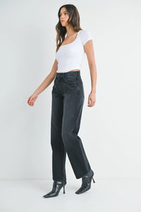 Women’s white short-sleeve crop top with black high-waisted relaxed fit straight leg denim jeans and black stiletto ankle boots