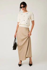 Beige satin maxi skirt with ruched details paired with black heels for an embroidered knit martini look