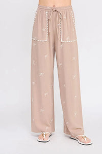 Beige embroidered linen pants with bow pattern and scallop trim, stylish linen pants