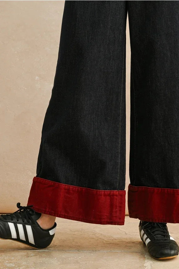 Black corduroy wide leg contrasted cuffed pants with red satin trim and adidas sneakers