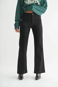 Black flare pants with patch pockets worn by a person, part of MINI PATCH POCKET FLARE JEANS collection