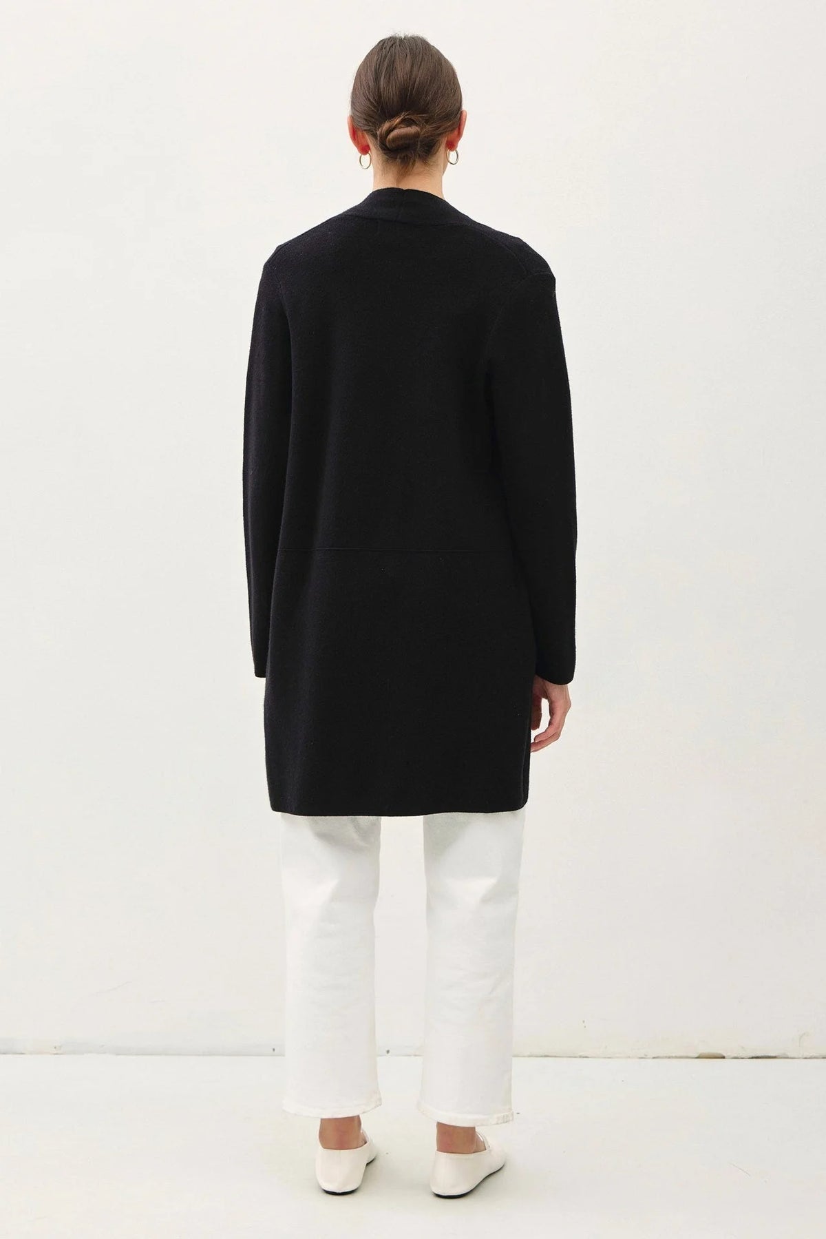 Black long-sleeved open cardigan over white pants, showcasing the classic knit coat style