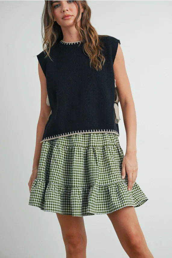 Mock neck sleeveless sweater in black with green gingham ruffle hem