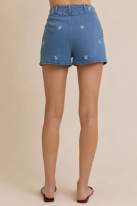 Blue denim floral embroidered pleated shorts displayed in FLORAL EMBROIDERED PLEATED DENIM SHORTS