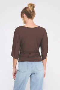 Brown double knit angel sleeve cinch side top with three-quarter sleeves and light wash wide-leg jeans