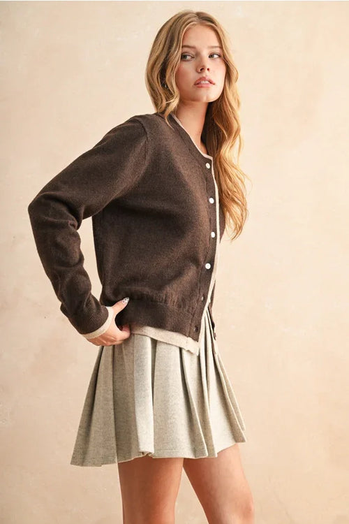 Color contrast button front cardigan with brown hue, white trim, and light pleated skirt