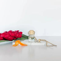 Car diffuser in clear glass bottle with wooden top and braided cord for women’s boho chic clothing