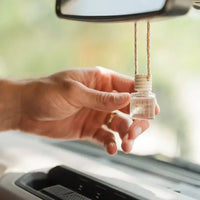 Small clear glass car diffuser with wooden cap and string for freshening car interiors