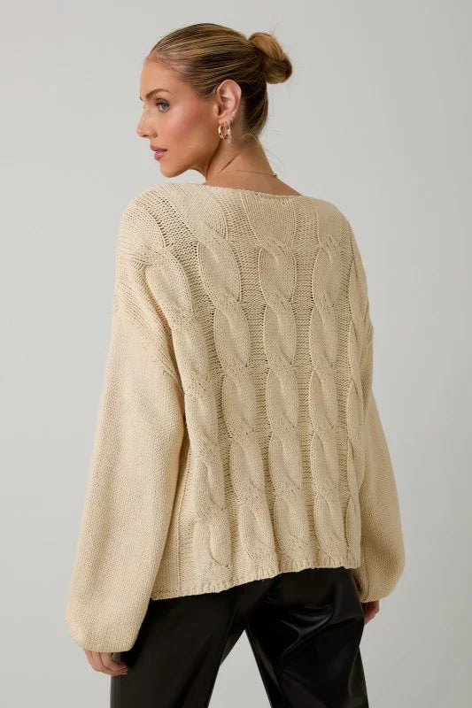 Cream cable knit tie front cardigan with black pants and gold hoop earrings