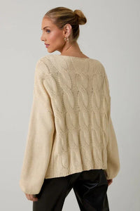 Cream cable knit tie front cardigan with black pants and gold hoop earrings