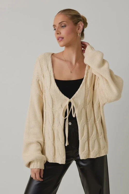 Cream cable knit tie front cardigan with drawstring closure and pockets