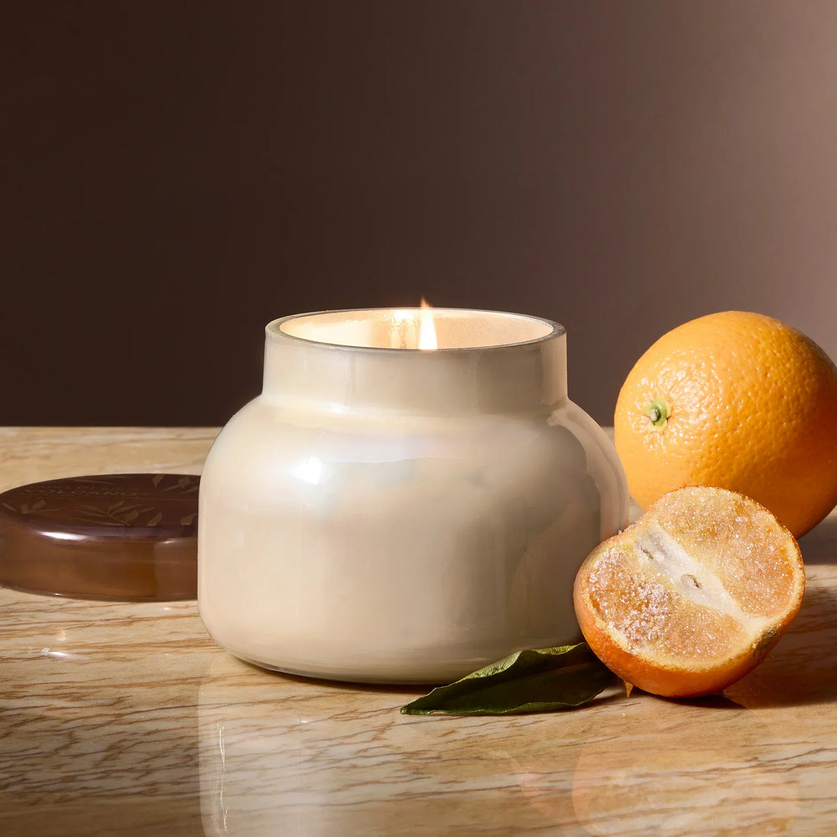 Cream-colored ceramic Capri Blue Volcano candle with orange slices and leaves for autumn glow