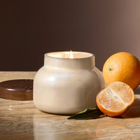 Cream-colored ceramic Capri Blue Volcano candle with orange slices and leaves for autumn glow