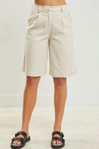Cream-colored wide leg half pants featuring pleats and a tailored waistband