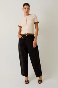 Cream-colored ribbed knit top with ruffled trim and leopard print piping detail