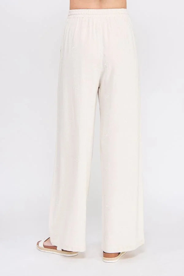 Cream-colored wide-leg embroidered linen pants with scallop trim for elegant style