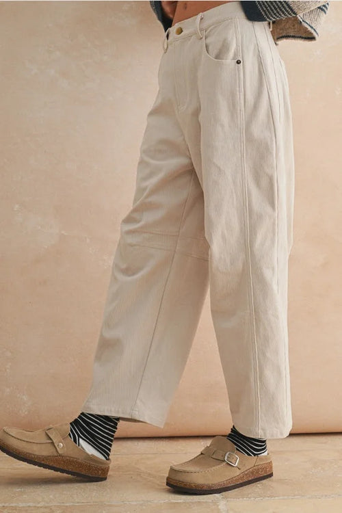 Cream-colored corduroy barrel pants with striped socks and brown loafers