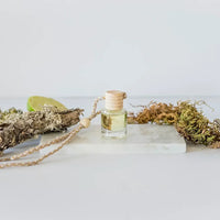 Small glass car diffuser with wooden cap and string for women’s boho chic clothing at Shop Daisy
