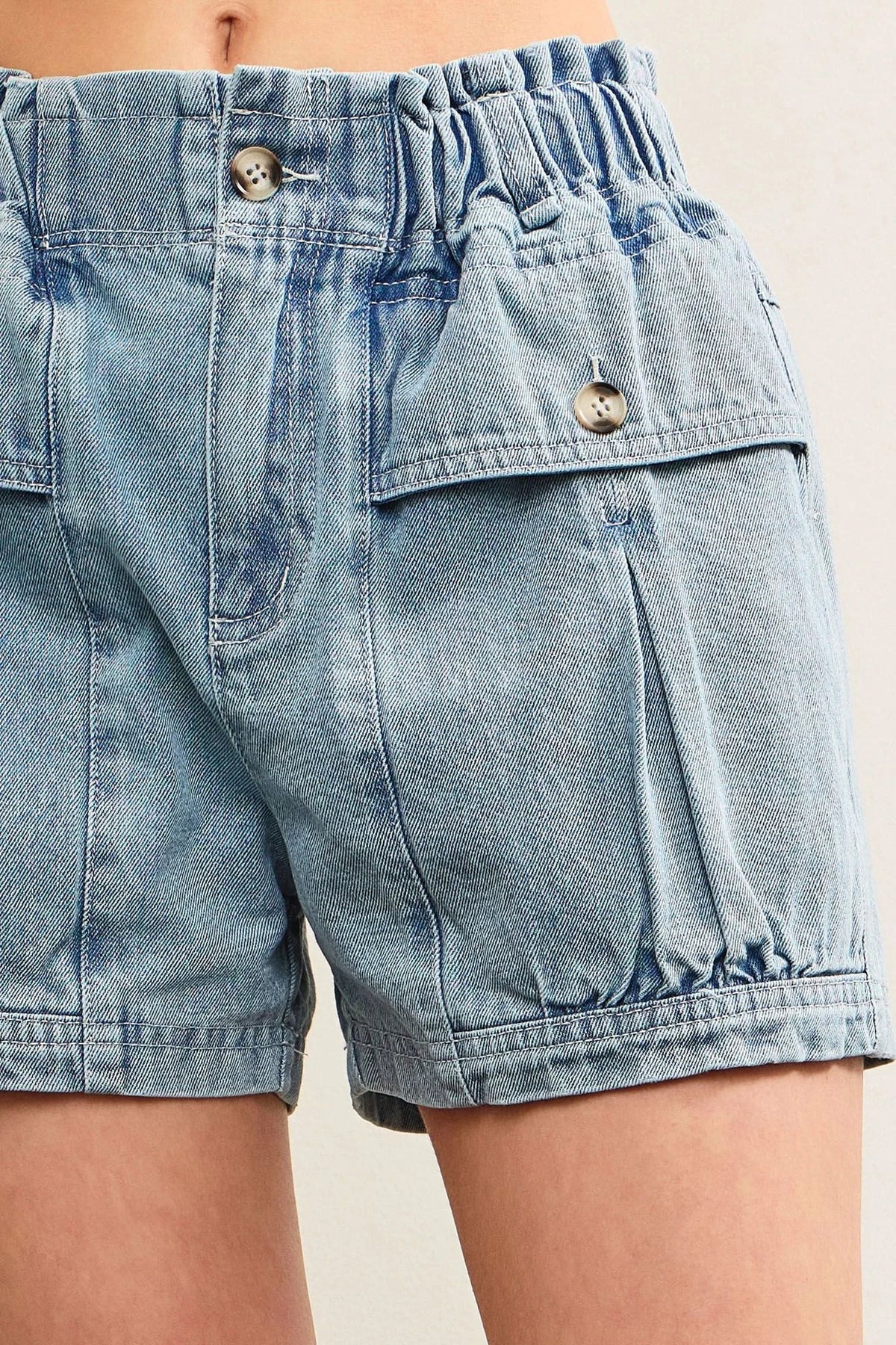 Light blue denim shorts with elastic waist and buttoned pockets for women’s boho chic clothing
