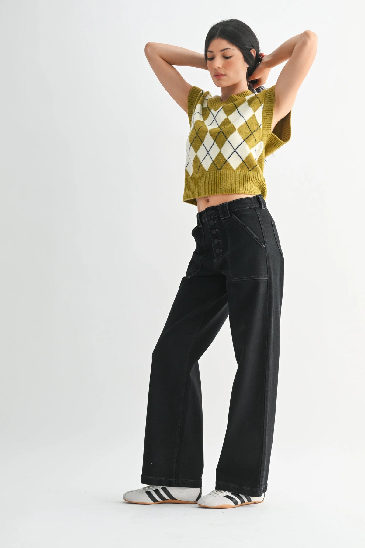 Mustard argyle sweater with slim wide leg denim pants and white sneakers