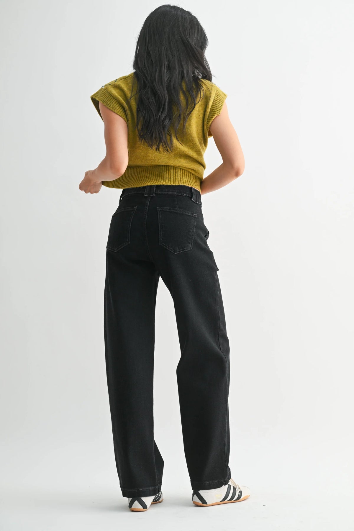 Mustard yellow ribbed knit top with slim wide leg denim pants and striped sneakers