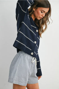 Navy blue striped collared cardigan with white buttons and drawstring hem