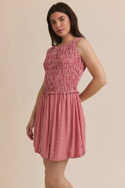 Red and white gingham plaid smocked sleeveless mini dress displayed in PLAID SMOCKED SLEEVELESS MINI DRESS