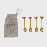 Gold-colored brass spoons with bee design in a printed drawstring bag for elegant storage