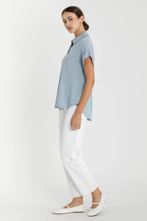 Woman wearing a blue shirt from SOLID SHORT SLEEVE BUTTON DOWN SHIRT, ideal for womenās boho chic clothing at Shop Daisy