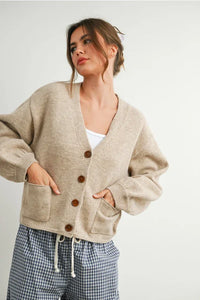Tan knit cardigan with brown buttons, front pockets, long sleeves, and V neck cuff button-up style