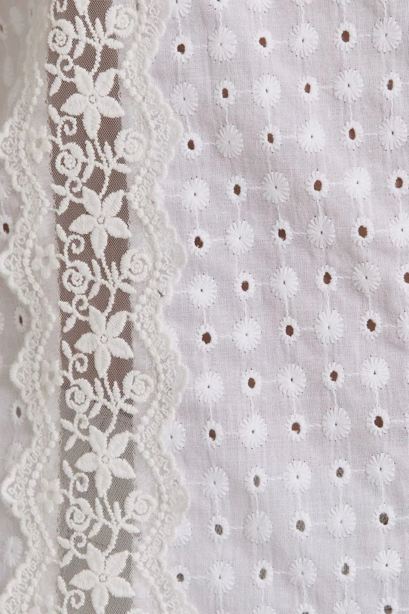 White eyelet fabric with floral lace trim showcases women’s boho chic clothing, shop Daisy