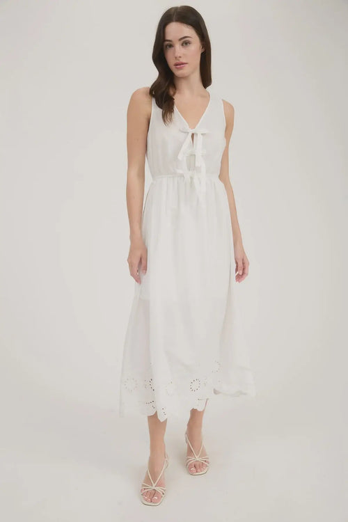 White sleeveless midi dress with bow tie and eyelet hem details, perfect for elegant occasions