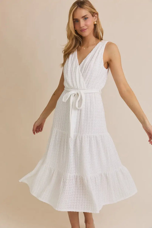 White sleeveless tiered dress with surplice sleeveless waist tie and eyelet details