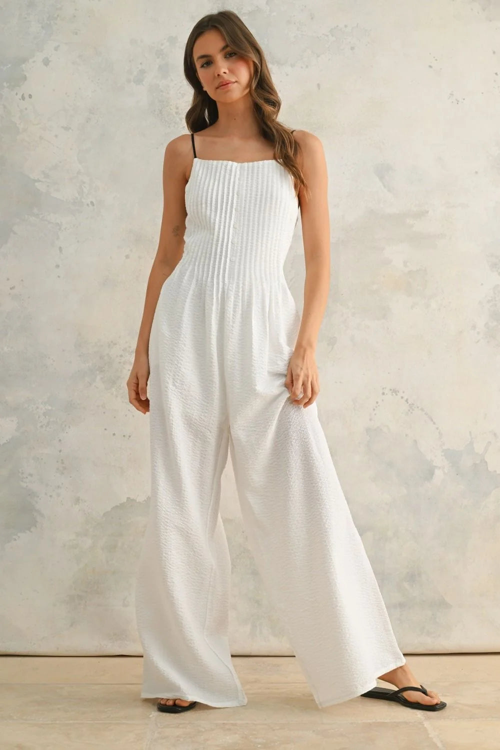 White wide-legged jumpsuit with contrast strap and spaghetti straps for a stylish look