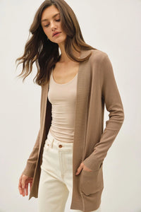 Woman wearing a beige cotton blend knit open front cardigan and tank top