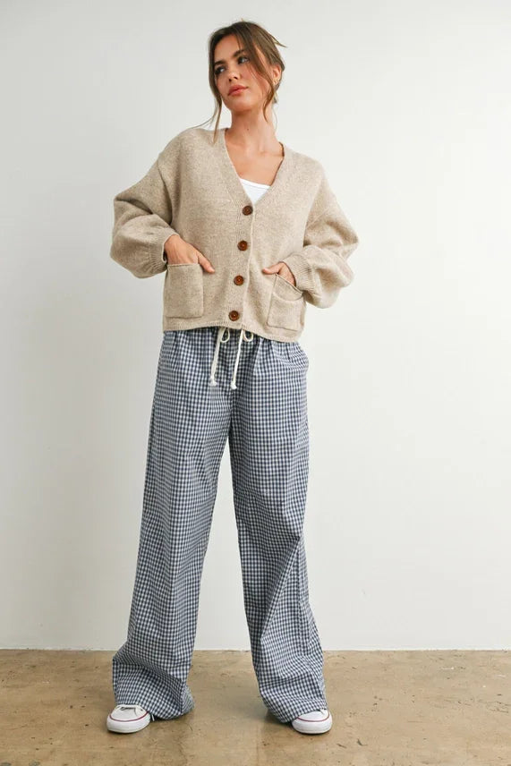 Woman modeling beige long sleeve neck cuff button-up cardigan with front pockets