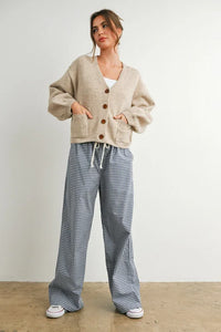 Woman modeling beige long sleeve neck cuff button-up cardigan with front pockets