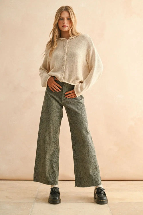 Woman wearing beige sweater and snakeskin snake print pants in a stylish outfit