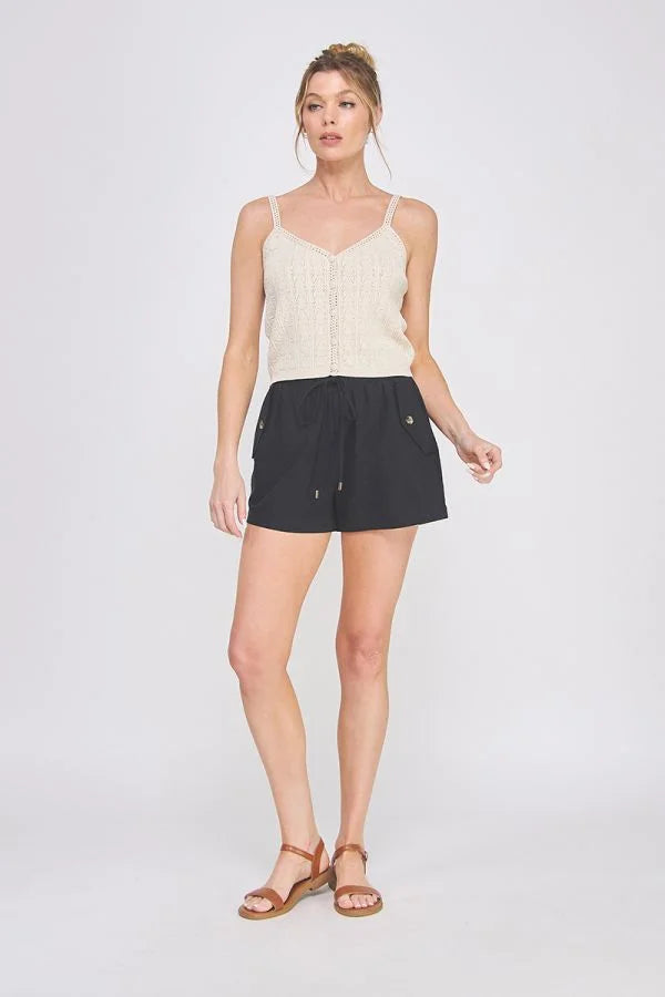 Woman wearing beige tank top and black woven elastic tie-waist shorts, women’s boho chic clothing from Shop Daisy