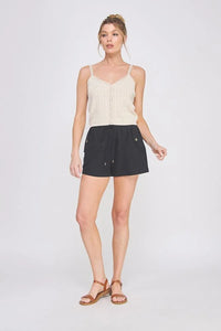 Woman wearing beige tank top and black woven elastic tie-waist shorts, women’s boho chic clothing from Shop Daisy