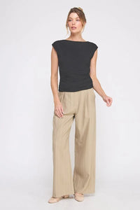 Woman wearing a black sleeveless boat neck scrunch tank top with beige wide-leg pants