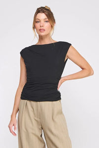 Woman wearing black sleeveless boat neck scrunch tank top with beige high-waisted trousers