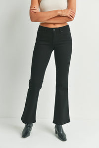 Woman wearing black low rise flare denim jeans and a cream crop top