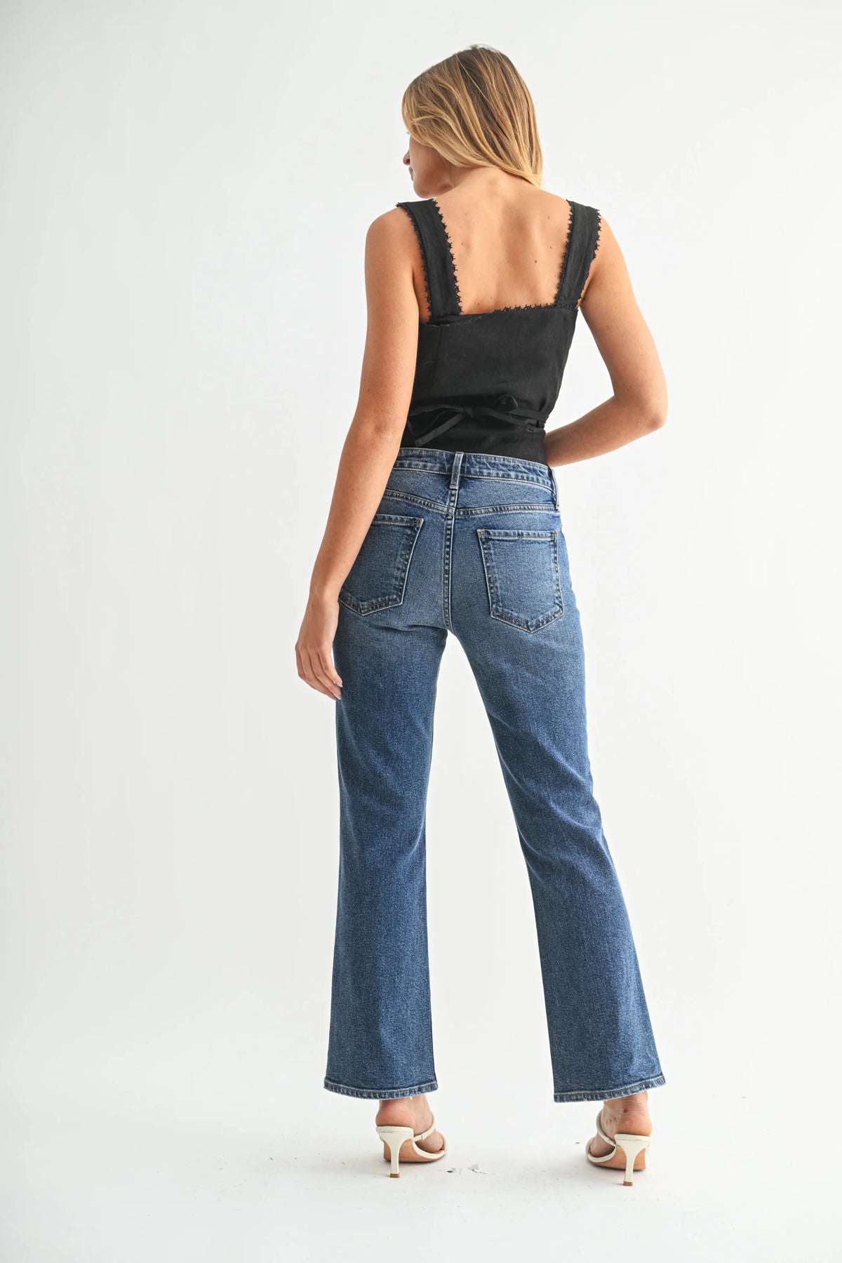 Woman modeling high rise slim cropped bootcut denim jeans with black sleeveless top