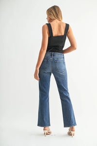 Woman modeling high rise slim cropped bootcut denim jeans with black sleeveless top