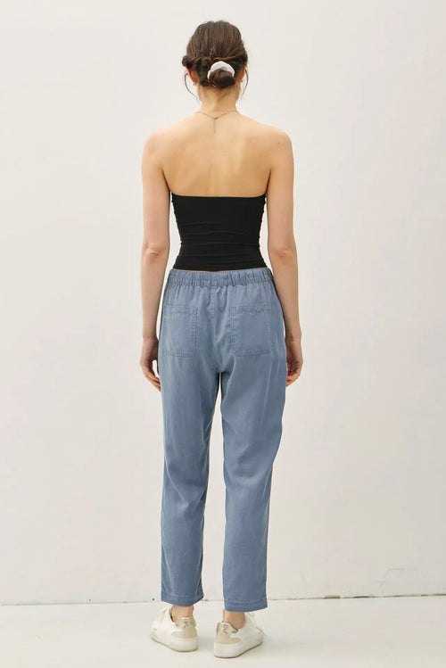 Woman wearing black tube top and blue TENCEL TAPERED PANTS for a stylish look