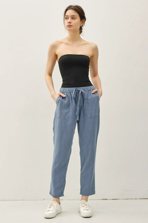 Woman wearing black tube top and blue TENCEL TAPERED PANTS, stylish tapered pants look
