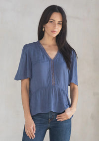 Woman modeling floral jacquard airy short sleeve peplum blouse with V-neck and dark jeans