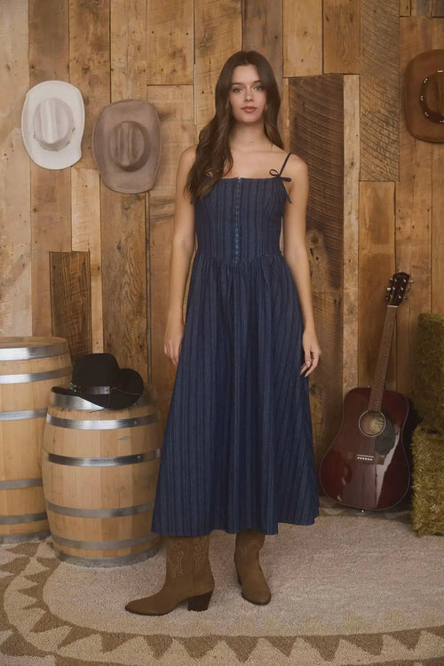 Woman in blue striped midi dress and brown boots, perfect womenās boho chic clothing from Shop Daisy
